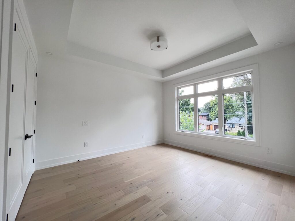 Modern large bedroom with a big window painted white in a custom house.